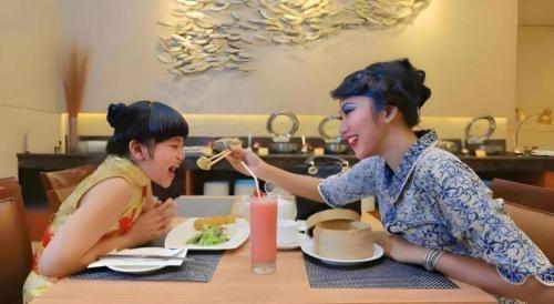 two women sitting at a table eating food at PARK HOTEL Cawang Jakarta in Jakarta