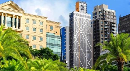 a tall building in a city with palm trees at Elysion Place Hotel Causeway Bay in Hong Kong