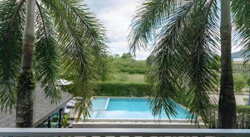 a view of a swimming pool between two palm trees at B2 Krabi Premier Hotel in Ao Nang Beach
