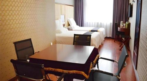 a hotel room with a table and two beds at GreenTree Inn Fuyang Yijing International North Business in Fuyang