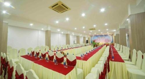 a large banquet hall with white chairs and red tables at Green Hotel Da Nang in Da Nang