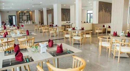 a dining room with tables and chairs with red pillows at Green Hotel Da Nang in Da Nang