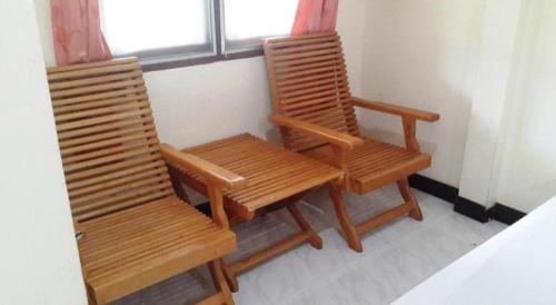 two wooden chairs sitting next to a window at Jinta Hotel Nathon Beach in Chaweng