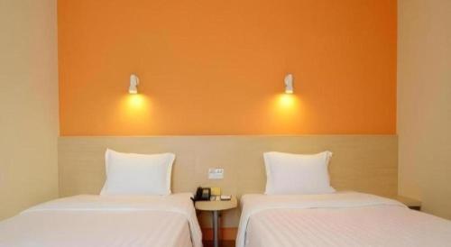 two beds sitting next to each other in a room at 7 Days Inn Hohhot Hailiang Xinhua Square Metro Station in Hohhot