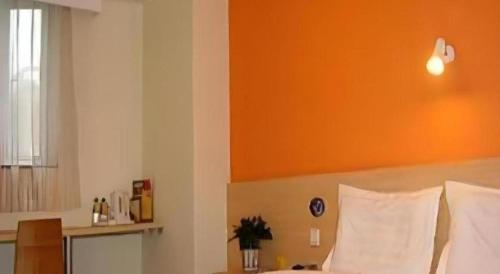 a bedroom with a bed with an orange wall at 7 Days Inn Hohhot Hailiang Xinhua Square Metro Station in Hohhot