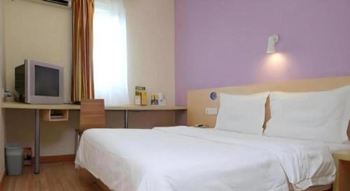 a bedroom with a white bed and a tv at 7 Days Inn Hohhot Hailiang Xinhua Square Metro Station in Hohhot
