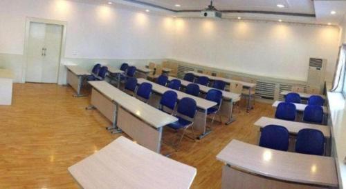a classroom with desks and blue chairs in a room at 7 Days Inn Hohhot Hailiang Xinhua Square Metro Station in Hohhot