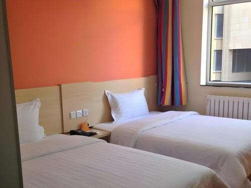 two beds in a hotel room with a window at 7 Days Inn Hohhot Hailiang Xinhua Square Metro Station in Hohhot