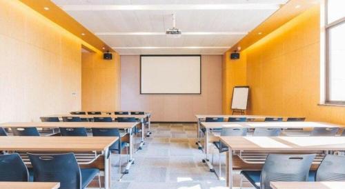an empty classroom with tables and chairs and a whiteboard at Atour Hotel Weihai Shidao in Dongshan