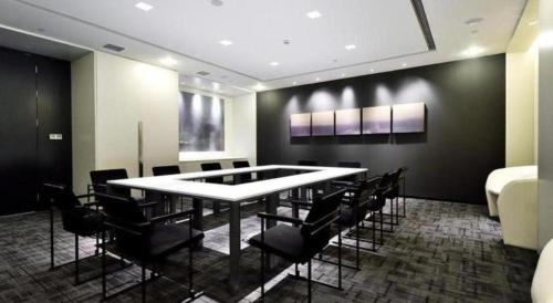 a room with a table and chairs and a bed at Jinjiang Metropolo Shanghai Xujiahui Nanhuating Hotel in Shanghai