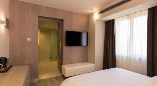 a bedroom with a bed and a tv on a wall at Jinjiang Metropolo Shanghai Xujiahui Nanhuating Hotel in Shanghai