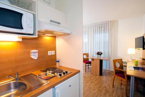 Cette chambre comprend une cuisine équipée d'un évier et d'un four micro-ondes. dans l'établissement Séjours & Affaires Rennes Longs Champs, à Rennes