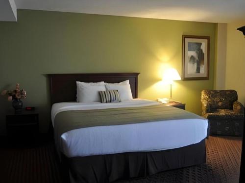 a hotel room with a large bed and a chair at Garden Plaza Hotel in Saddle Brook