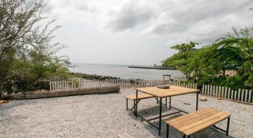 a picnic table and a bench next to the water at OYO 931 Sor Chareanpanit in Pattaya Central