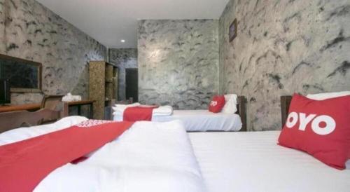 a bedroom with two beds with red and white pillows at OYO 75374 Baan Rak Mai in Kanchanaburi