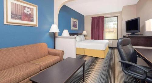a hotel room with a couch and a bed at Baymont By Wyndham Laurel in Laurel