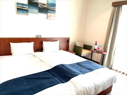 a bedroom with a large bed with a blue blanket at THE GRAND HOTEL GINOWAN in Ginowan