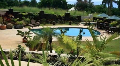 a swimming pool in a garden with trees and plants at Le Manumea Hotel in Apia