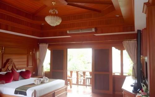 a bedroom with a bed with red pillows and a television at Ngamta Hotel in Mae Hong Son