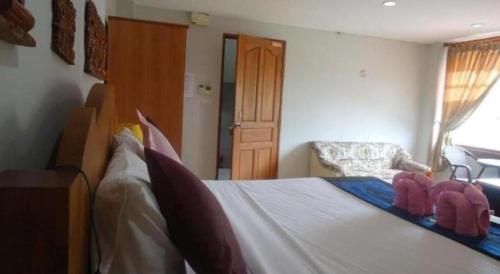 a bedroom with a large bed and a chair at Ngamta Hotel in Mae Hong Son