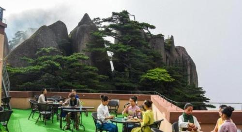 a group of people sitting at tables in front of a mountain at Huangshan Yupinglou Hotel in Huangshan