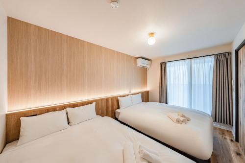 two beds in a room with a window at Apartment Hotel 11 Villa Hanazonocho in Osaka
