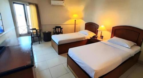 a hotel room with two beds and a window at Alexander Hotel Tegal in Tegal