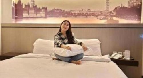 a woman sitting on a bed with pillows at Alexander Hotel Tegal in Tegal