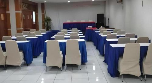 a row of tables and chairs with blue table cloth at Alexander Hotel Tegal in Tegal