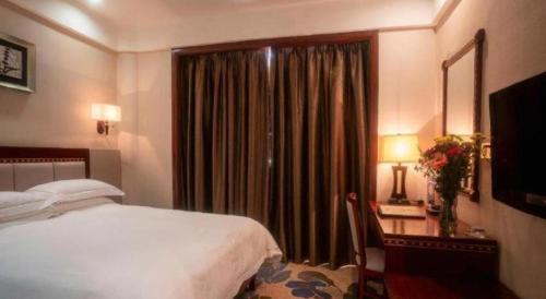 a bedroom with a bed and a desk and a window at Dong Cheng Hotel in Shunde