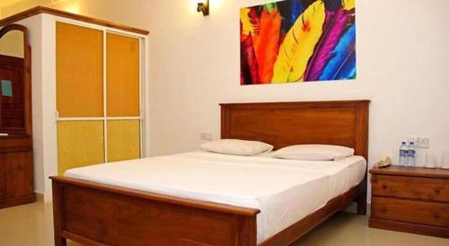 a bedroom with a bed with a painting on the wall at OYO 246 Roy Villa Beach Hotel in Beruwala
