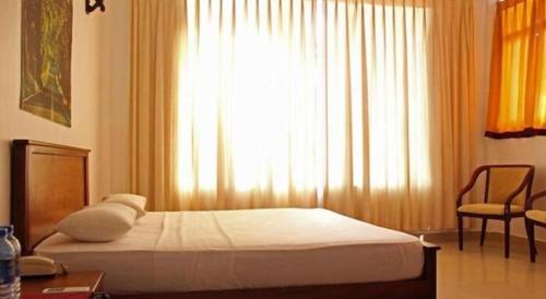 a bedroom with a bed with a window and a chair at OYO 246 Roy Villa Beach Hotel in Beruwala