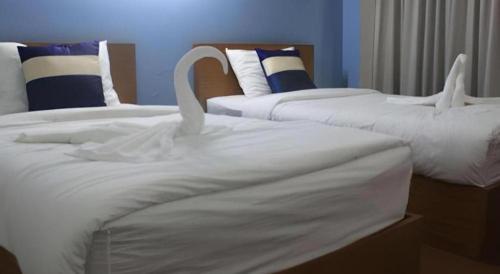 two beds with white sheets and swans on them at Urban House 195 in Chiang Mai