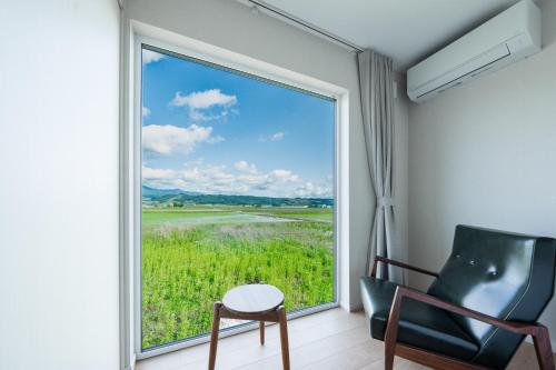 a room with a chair and a window with a view at Yugen Retreats Furano in Kami-furano