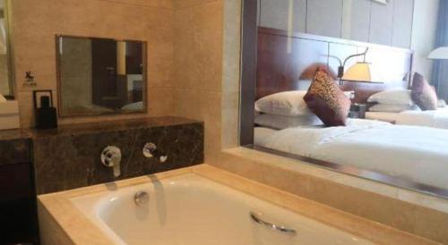 a bathroom with a tub and a bed with a mirror at Xi'an Airport Hotel in Xi'an