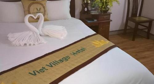 two white swans are sitting on a bed at Viet Village Hotel in Hanoi