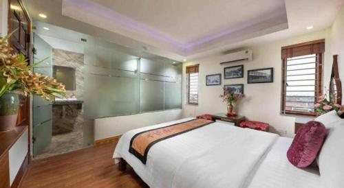 a bedroom with a large white bed and a bathroom at Viet Village Hotel in Hanoi