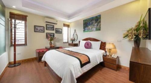 a bedroom with a large white bed and a dresser at Viet Village Hotel in Hanoi