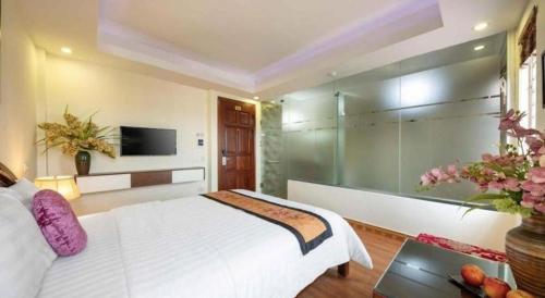 a bedroom with a large white bed and a tv at Viet Village Hotel in Hanoi