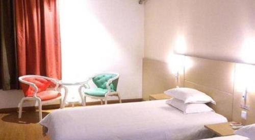 a hotel room with two chairs and a bed at Ibis Nantong Qingnian in Nantong
