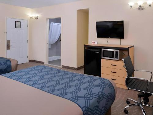a hotel room with a bed and a flat screen tv at Econo Lodge Rochester I-90 & I-390 in Rochester