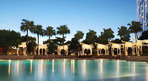 a large swimming pool with a building and palm trees at City of Dreams - The Countdown Hotel in Macau