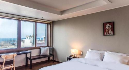 a bedroom with a bed and a desk and a window at Check Inn Hotel in Jeju