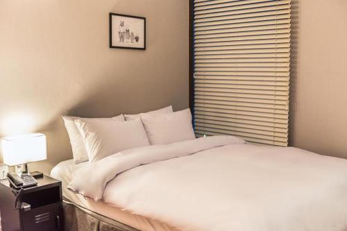 a bedroom with a white bed and a window at Check Inn Hotel in Jeju