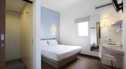 a white bedroom with a bed and a bathroom at Amaris Hotel Pakuan Bogor in Bogor