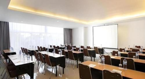 a conference room with tables and chairs and a screen at Amaris Hotel Pakuan Bogor in Bogor