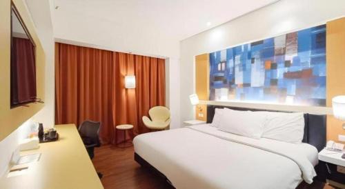 a hotel room with a white bed and a desk at Brits Hotel Karawang in Karawang