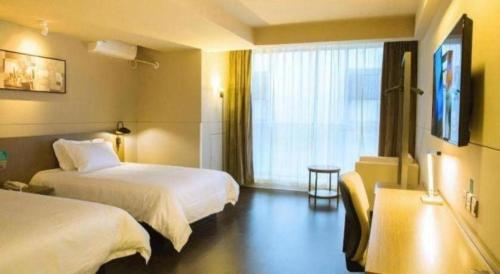 a hotel room with two beds and a window at Jinjiang Inn Select Kunming High-speed South Railway University Town in Kunming