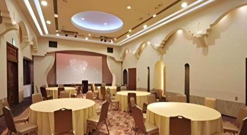 a room with tables and chairs and a projection screen at Daini Fuji Hotel in Nagoya