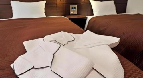 two beds in a hotel room with white sheets at Daini Fuji Hotel in Nagoya